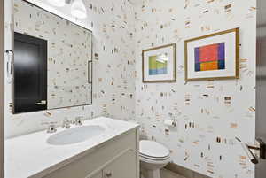 Bathroom with vanity, wallpapered walls, and dark tile patterned floors