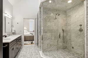 Bathroom with double vanity, ensuite bathroom, vaulted ceiling, and a stall shower