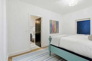 Bedroom featuring light wood finished floors, connected bathroom, and wallpapered walls