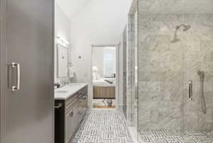 Ensuite bathroom featuring double vanity, lofted ceiling, and a stall shower