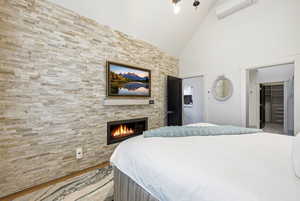 Bedroom with a fireplace, lofted ceiling, a walk in closet, and cooling unit