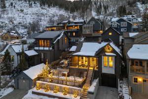Snow covered back of property featuring concrete driveway, a mountain view, and a garage
