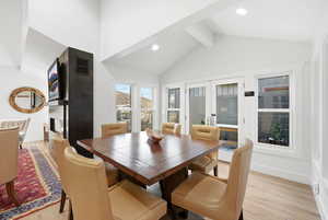 Dining room with light wood-style flooring, french doors, a fireplace, recessed lighting, and lofted ceiling