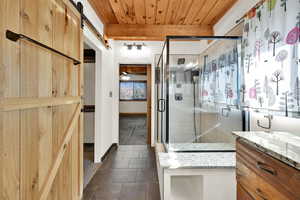 Full bathroom with a shower stall, vanity, wooden ceiling, ceiling fan, and dark tile patterned flooring