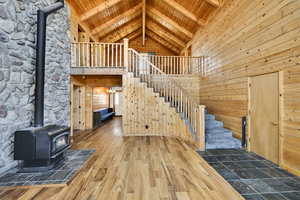 Stairs featuring a wood stove, hardwood / wood-style flooring, a high ceiling, a wooden ceiling with exposed beams, and wooden walls