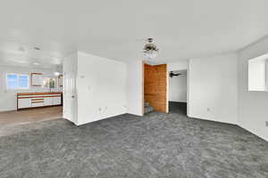 Unfurnished living room with carpet floors and a ceiling fan