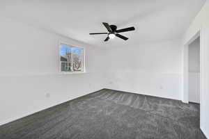 Empty room with dark carpet and ceiling fan