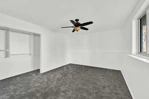 Unfurnished bedroom featuring dark carpet, a ceiling fan, and a closet
