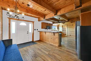 Kitchen featuring stainless steel appliances, hanging light fixtures, wood walls, brown cabinetry, and light countertops