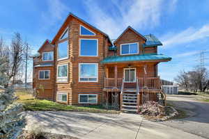 Log cabin featuring covered porch, stairs, log siding, driveway, and a metal roof