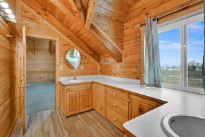 Kitchen featuring light countertops, wood walls, light wood-style flooring, wood ceiling, and vaulted ceiling
