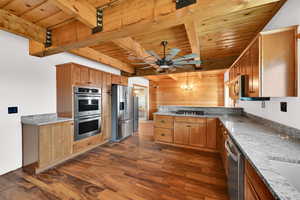 Kitchen featuring dark wood-style floors, a wooden ceiling with exposed beams, appliances with stainless steel finishes, a chandelier, and a peninsula