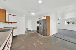 Kitchen with brown cabinets, white cabinetry, and ceiling fan