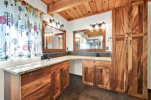 Full bath with vanity, a wood ceiling with exposed beams, and dark tile patterned floors