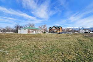 View of green lawn featuring a mountain view and an outbuilding
