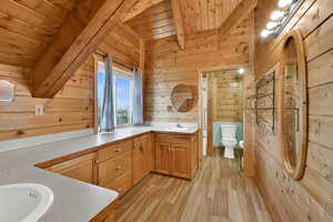 Bathroom featuring wood walls, vanity, light wood-style floors, and wood ceiling