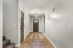 Doorway to outside with a textured ceiling and tile patterned floors