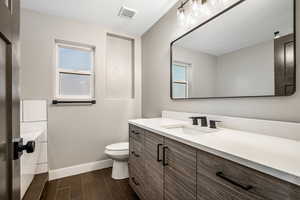 Full bath with vanity, wood finish floors, and a textured ceiling