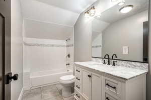 Full bathroom with vanity, bathing tub / shower combination, lofted ceiling, and light tile patterned floors