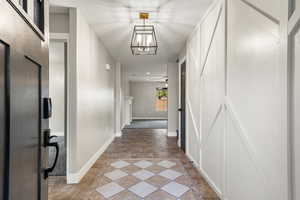 Hallway with suspended lighting, inlaid floor details, and a textured ceiling