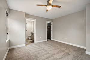 Unfurnished bedroom with light colored carpet, a ceiling fan, and ensuite bath