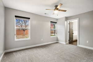 Unfurnished bedroom featuring light colored carpet, a ceiling fan, ensuite bath, and a textured ceiling