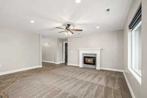 Unfurnished living room with a glass covered fireplace, a ceiling fan, recessed lighting, and carpet floors