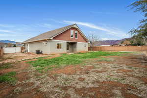 Back of house featuring a mountain view, a fenced backyard, and stucco siding