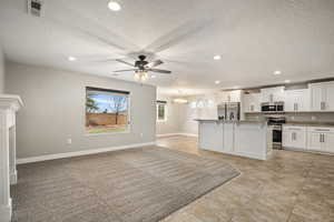 Kitchen with white cabinets, stainless steel appliances, ceiling fan, a textured ceiling, and a center island
