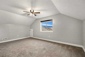 Bonus room with carpet flooring, a textured ceiling, and a ceiling fan