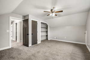 Additional living space with built in shelves, a textured ceiling, light carpet, and a ceiling fan