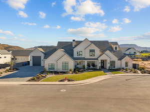 View of front of home featuring decorative driveway, a mountain view, stone siding, and a front yard