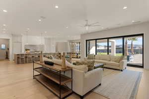 Living room with a ceiling fan, light wood finished floors, and hanging lights