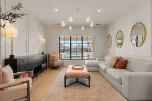 Living room with a decorative wall, light wood-style flooring, and hanging lights