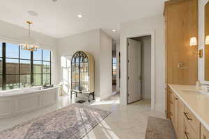 Bathroom featuring a bath, vanity, and a chandelier