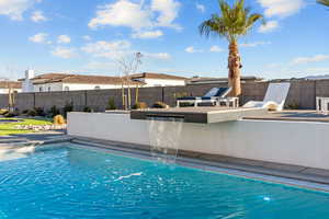 View of swimming pool with a fenced backyard, an outdoor kitchen, and patio surround