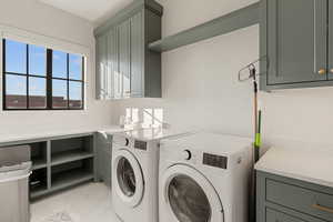 Laundry room featuring washer and dryer, cabinet space, and light tile patterned flooring