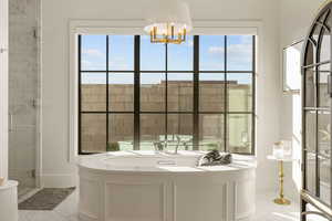 Full bathroom featuring a bath, a shower stall, and hanging lights