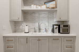 Kitchen with light stone counters, backsplash, and open shelves
