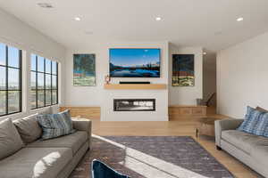 Living area featuring recessed lighting, wood finished floors, and a glass covered fireplace
