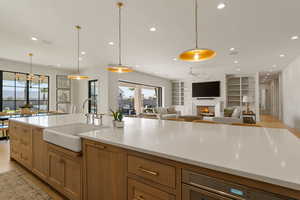 Kitchen with built in shelves, hanging light fixtures, a fireplace, open floor plan, and light wood-style floors