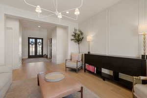 Living area with a decorative wall, light wood-style floors, french doors, and recessed lighting