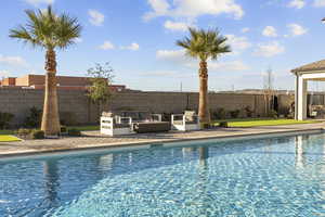 View of pool with an outdoor lounge area, a fenced backyard, and patio surround