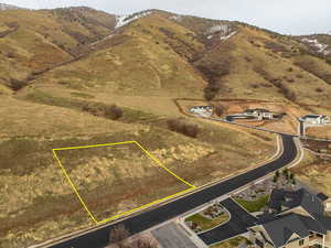 Aerial view of property and surrounding area featuring a mountainous background and property boundaries highlighted