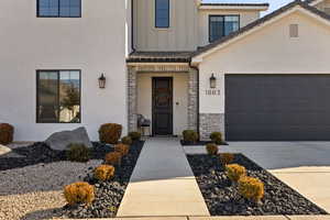 View of exterior entry with board and batten siding, brick siding, concrete driveway, and an attached garage