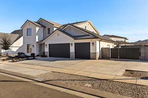 Modern inspired farmhouse featuring a gate, concrete driveway, an attached garage, stucco siding, and brick siding