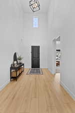 Foyer entrance with a high ceiling, light wood-style flooring, and hanging lights