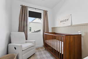 Bedroom featuring a crib and a wainscoted wall