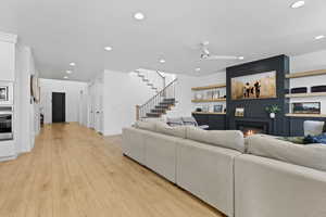 Living area with a fireplace, light wood finished floors, a ceiling fan, and recessed lighting