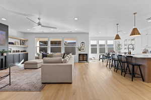 Living room with ceiling fan, light wood finished floors, and recessed lighting
